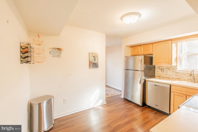 kitchen featuring a sink, appliances with stainless steel finishes, light brown cabinetry, and light countertops