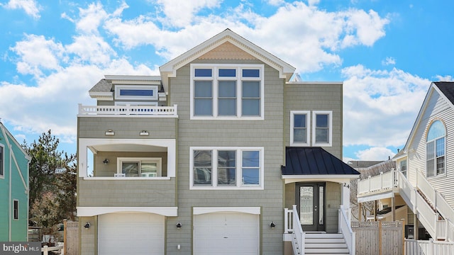 view of front of property with a balcony, metal roof, a standing seam roof, and fence