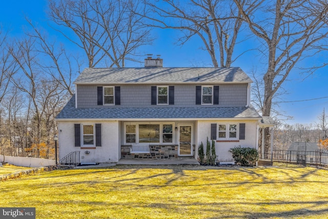 view of front facade featuring a front lawn, fence, a porch, roof with shingles, and a chimney