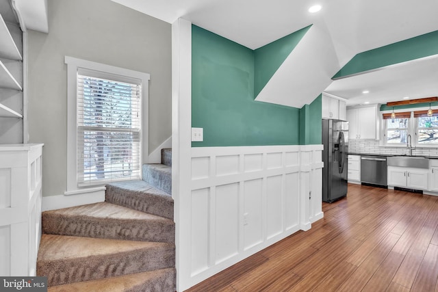 stairs with recessed lighting, a wainscoted wall, and wood finished floors