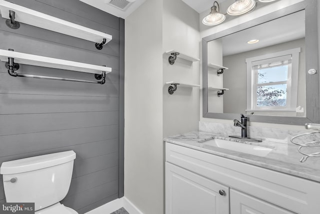 half bath featuring vanity, toilet, and visible vents