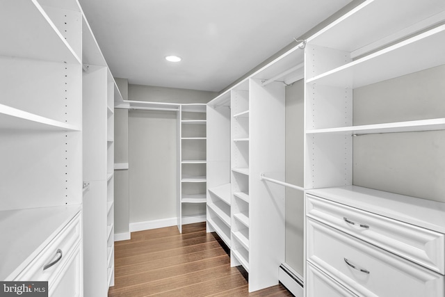 walk in closet with baseboard heating and dark wood-style flooring