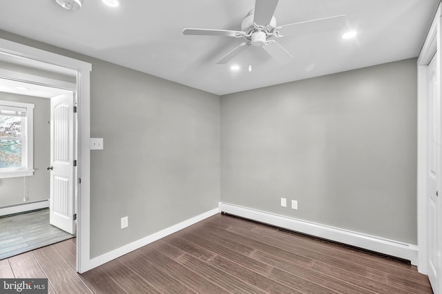 empty room with baseboards, baseboard heating, wood finished floors, and a ceiling fan