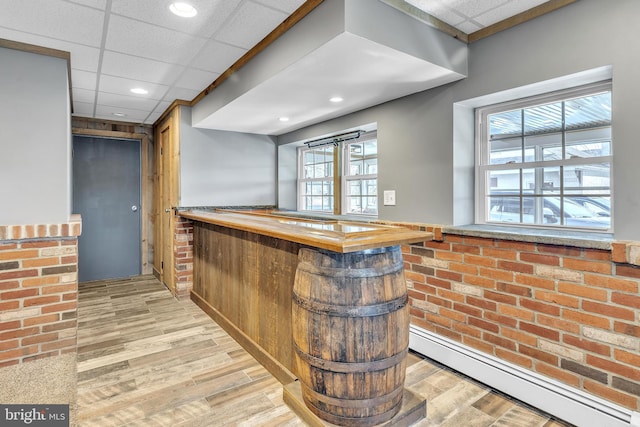 bar featuring light wood-type flooring, a baseboard heating unit, recessed lighting, a paneled ceiling, and a dry bar