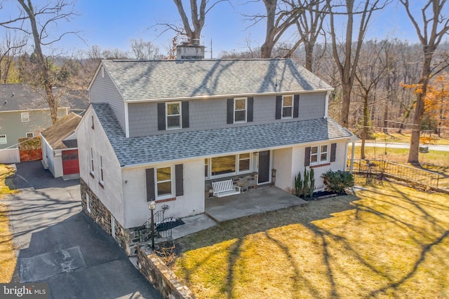 traditional home with a chimney, a shingled roof, a front yard, and fence