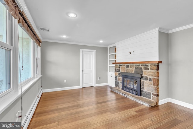 unfurnished living room with visible vents, baseboards, ornamental molding, a stone fireplace, and wood finished floors