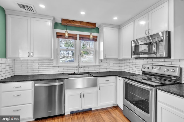 kitchen with a sink, visible vents, appliances with stainless steel finishes, and white cabinets