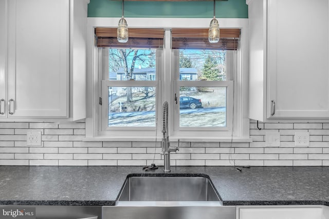 kitchen featuring a sink, decorative light fixtures, backsplash, and white cabinets