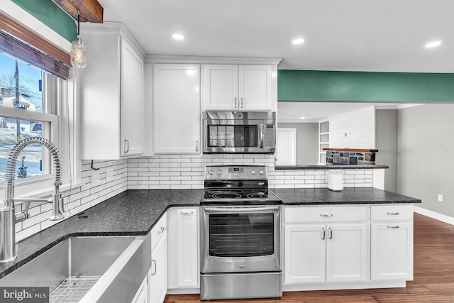 kitchen featuring a sink, a peninsula, appliances with stainless steel finishes, and white cabinets