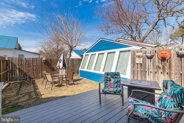 wooden terrace featuring an outbuilding, outdoor dining area, and a fenced backyard