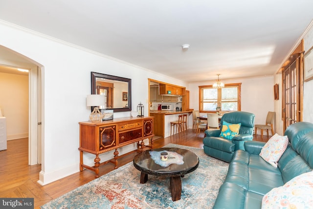 living room with light wood-type flooring, baseboards, a chandelier, and crown molding