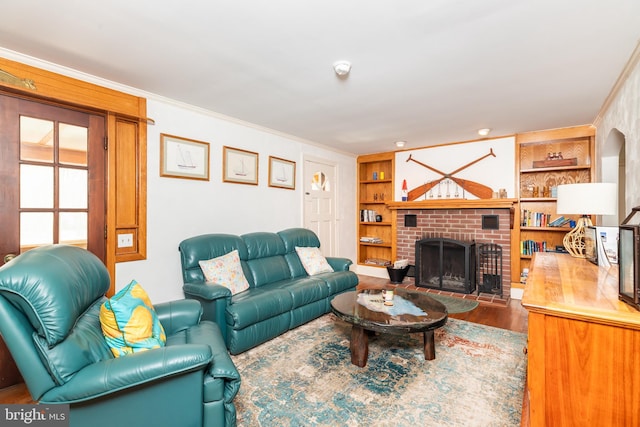 living room featuring built in features, wood finished floors, a fireplace, and crown molding