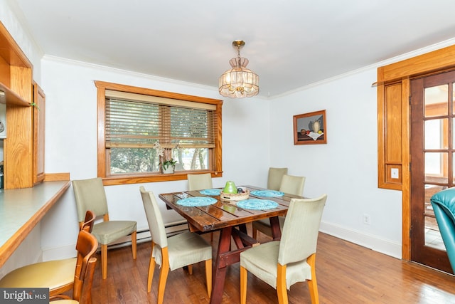 dining room featuring baseboards, a notable chandelier, wood finished floors, and ornamental molding