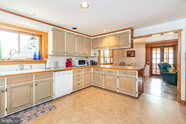 kitchen featuring white appliances, light countertops, a peninsula, and a sink