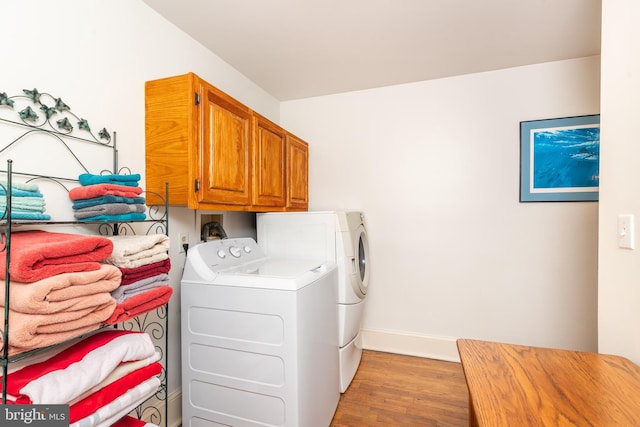 washroom with washer and dryer, cabinet space, light wood-type flooring, and baseboards