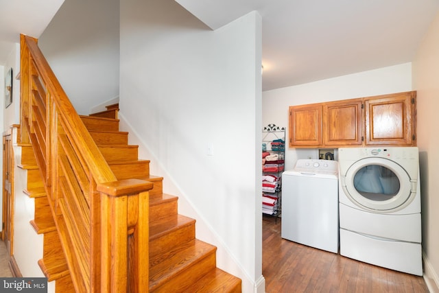 laundry room featuring hardwood / wood-style floors, cabinet space, baseboards, and washing machine and clothes dryer