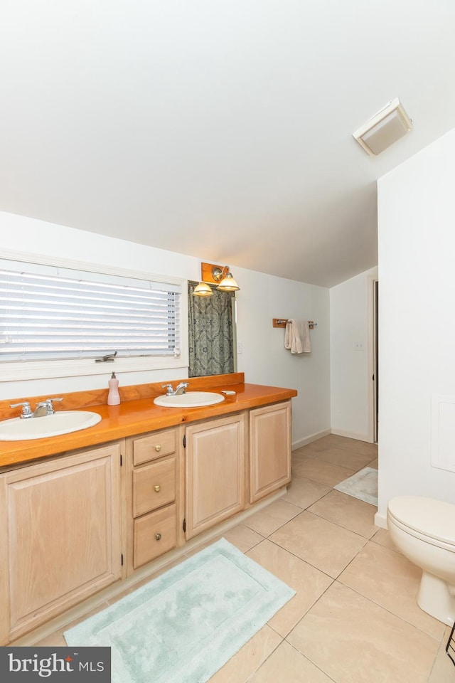 bathroom featuring tile patterned floors, double vanity, toilet, and a sink