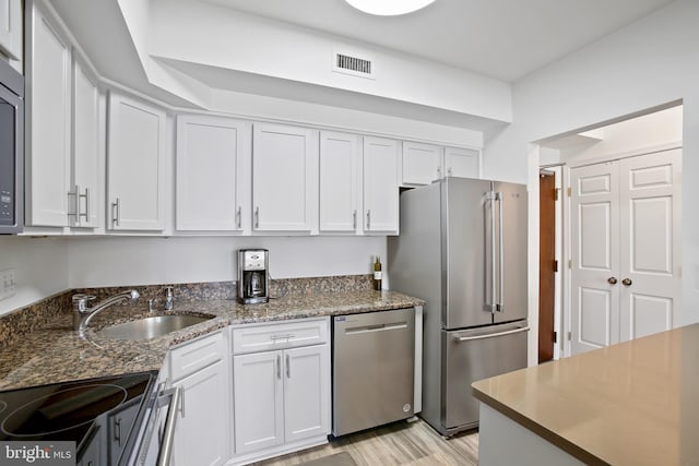 kitchen with visible vents, appliances with stainless steel finishes, light wood-style floors, white cabinets, and a sink