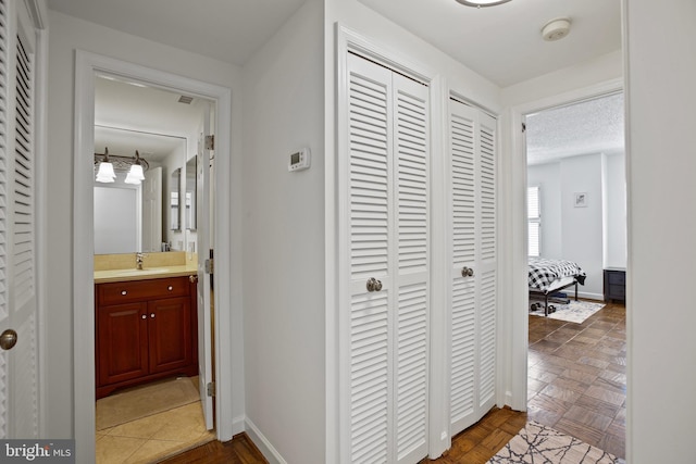 hall with visible vents, baseboards, and a sink