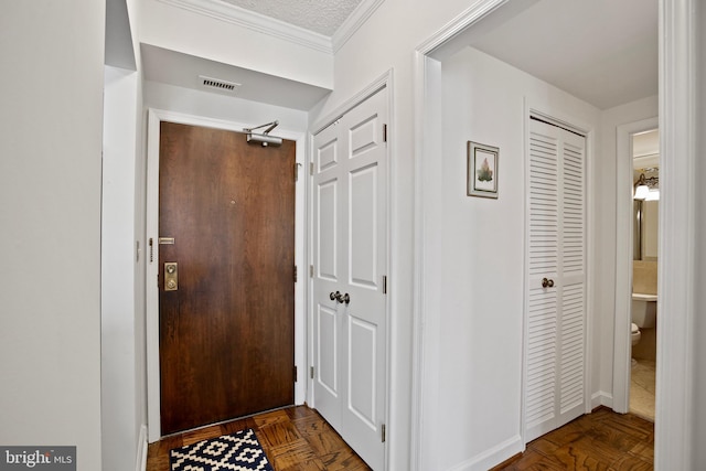 hall with visible vents, a textured ceiling, and crown molding