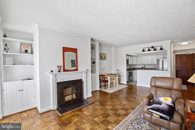 living room featuring baseboards, a textured ceiling, a glass covered fireplace, and ornamental molding