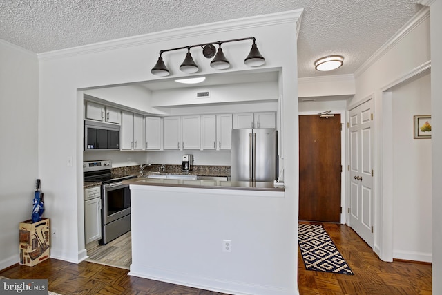 kitchen with visible vents, ornamental molding, appliances with stainless steel finishes, a textured ceiling, and dark countertops