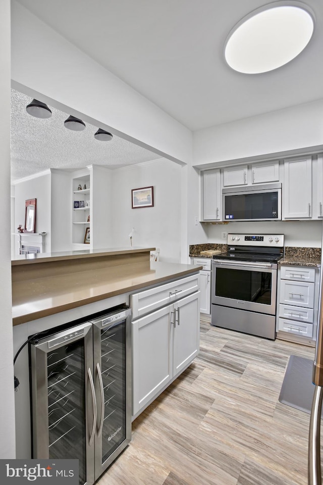 kitchen with stainless steel appliances, wine cooler, a textured ceiling, and dark countertops