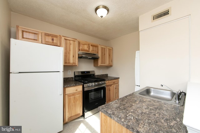 kitchen with visible vents, stainless steel range with gas cooktop, freestanding refrigerator, a sink, and under cabinet range hood