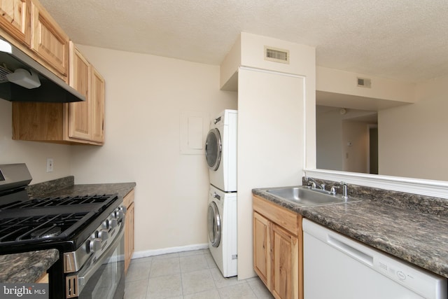 kitchen with stainless steel range with gas cooktop, white dishwasher, a sink, stacked washer / drying machine, and under cabinet range hood