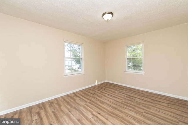 empty room with a healthy amount of sunlight, light wood-style floors, and baseboards