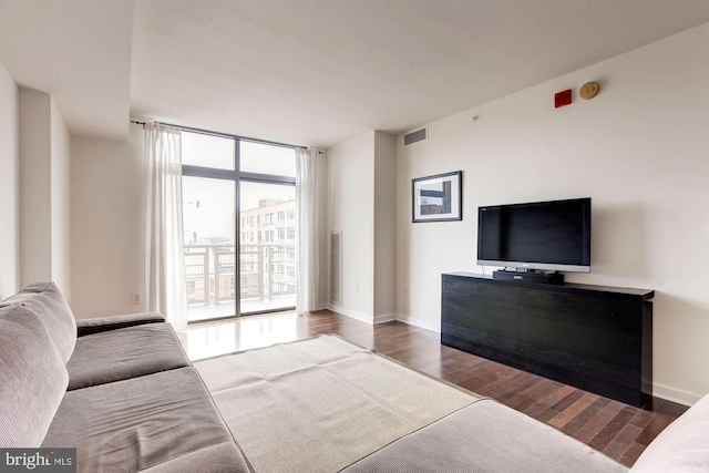 living area featuring visible vents, floor to ceiling windows, baseboards, and wood finished floors