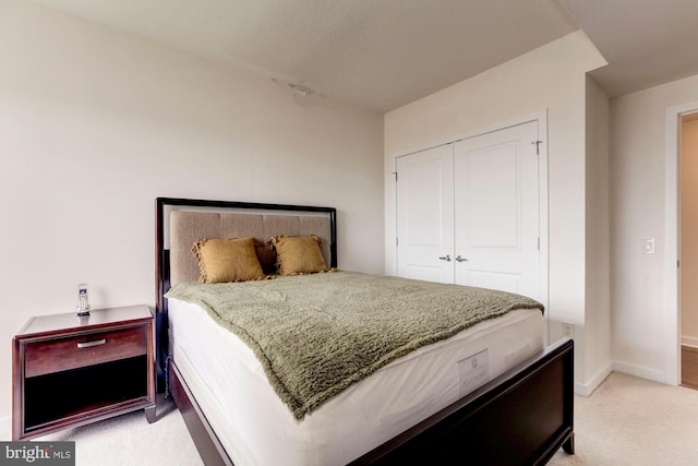 bedroom featuring a closet, light colored carpet, and baseboards