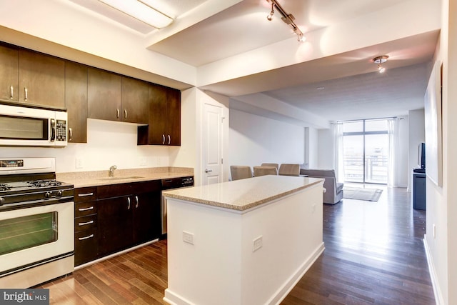 kitchen with a wall of windows, dishwashing machine, dark wood-style floors, stainless steel gas range, and open floor plan