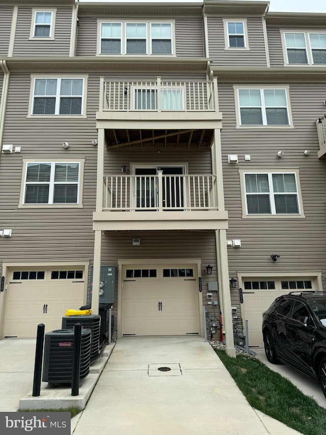 rear view of property featuring an attached garage, central AC unit, and driveway