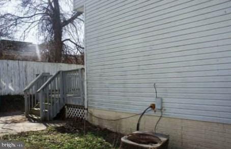 view of side of property with central AC and fence