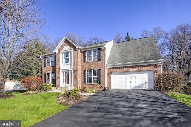 colonial home featuring aphalt driveway, an attached garage, and brick siding