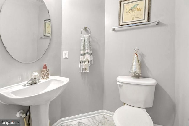 bathroom featuring a sink, baseboards, toilet, and marble finish floor