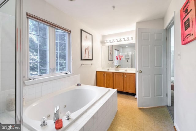 full bath featuring a stall shower, a sink, plenty of natural light, a tub with jets, and double vanity