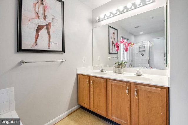 full bath featuring a sink, baseboards, double vanity, and a shower stall