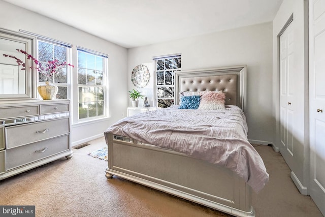 carpeted bedroom with visible vents, baseboards, and a closet