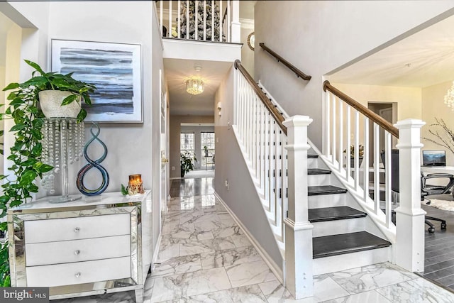 stairs with baseboards, a notable chandelier, and marble finish floor