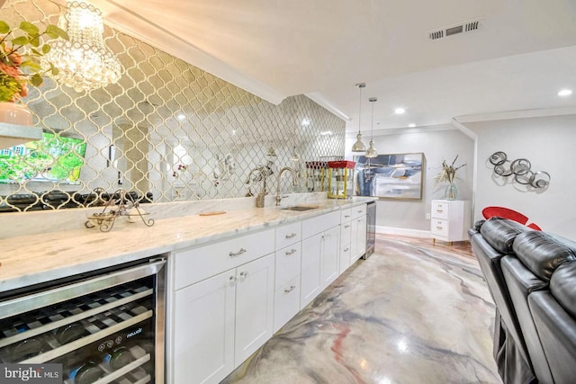 interior space with beverage cooler, ornamental molding, light stone counters, white cabinets, and a sink