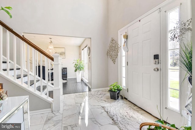 foyer entrance with stairs, plenty of natural light, baseboards, and marble finish floor