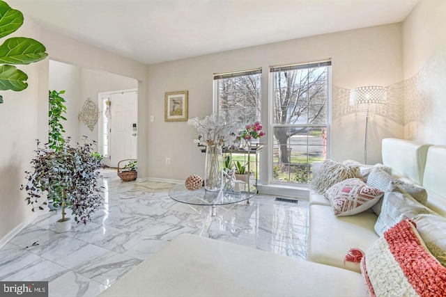 interior space featuring plenty of natural light, visible vents, marble finish floor, and baseboards