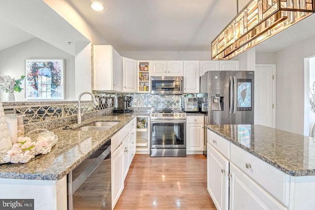 kitchen with decorative backsplash, appliances with stainless steel finishes, dark stone counters, and a sink