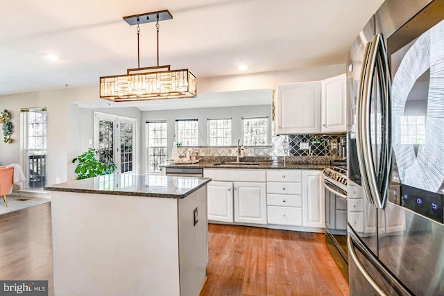 kitchen featuring decorative backsplash, appliances with stainless steel finishes, light wood-style floors, white cabinets, and a sink