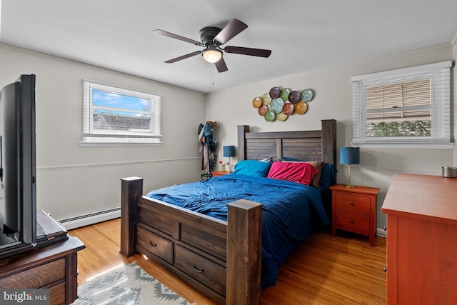 bedroom with ceiling fan, baseboard heating, and wood finished floors