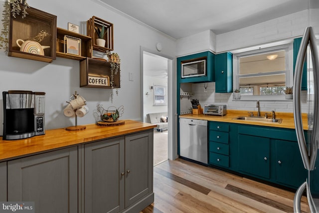 kitchen featuring tasteful backsplash, wooden counters, stainless steel appliances, and a sink