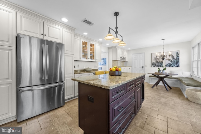 kitchen featuring visible vents, white cabinetry, stone tile flooring, and freestanding refrigerator