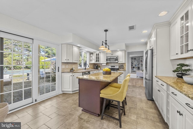 kitchen featuring tasteful backsplash, a kitchen island, stone tile flooring, stainless steel appliances, and a sink